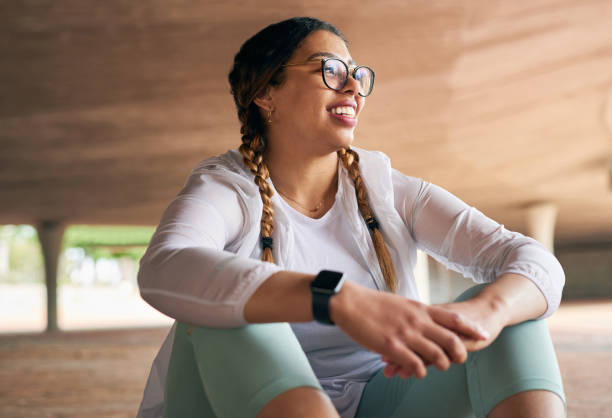 tiro de uma jovem esportiva fazendo uma pausa enquanto se exercita ao ar livre - women smiling happiness healthy lifestyle - fotografias e filmes do acervo