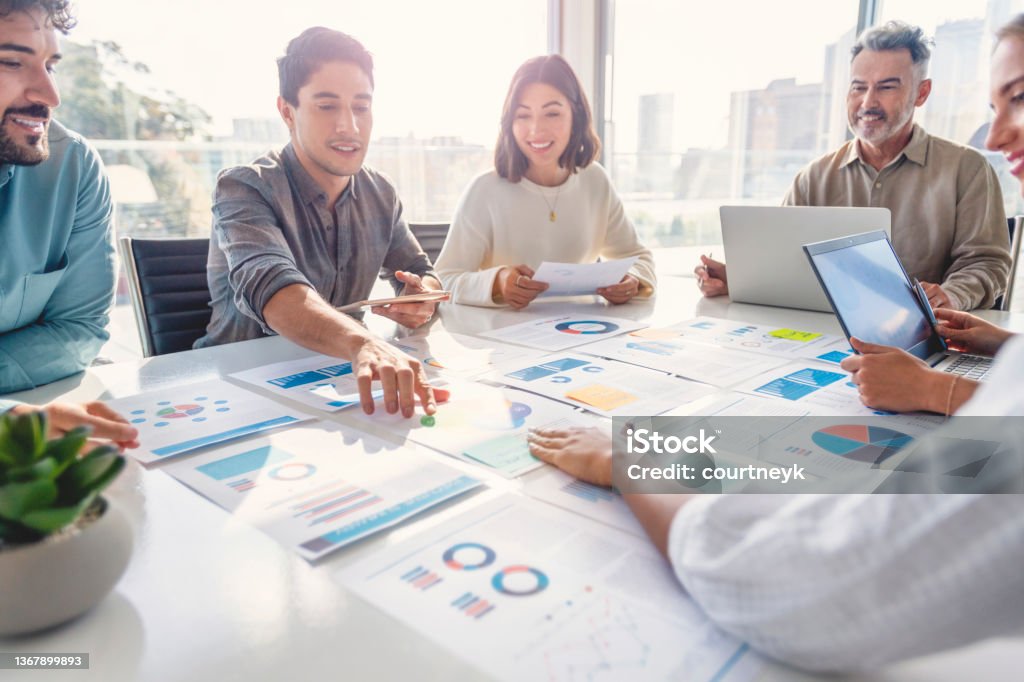 Grup divers de persoane care lucrează cu documente pe o masă din sala de consiliu la o prezentare de afaceri sau la un seminar. Documentele au cifre financiare sau de marketing, grafice și diagrame pe ele. Există laptopuri și tablete digitale pe masă - Fotografie de stoc Marketing fără redevențe Grup divers de persoane care lucrează cu documente pe o masă din sala de consiliu la o prezentare de afaceri sau la un seminar. Documentele au cifre financiare sau de marketing, grafice și diagrame pe ele. Există laptopuri și tablete digitale pe masă - Fotografie de stoc Marketing fără redevențe