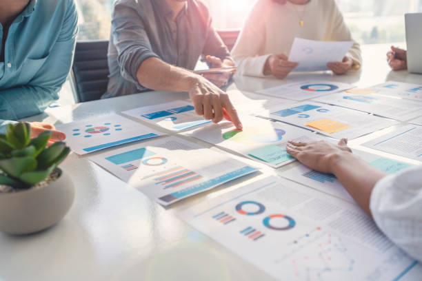 istock Multi racial group of people working with Paperwork on a board room table at a business presentation or seminar. 1367899895