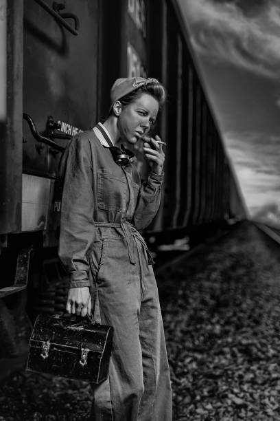 Vintage dirty female worker having her cigarette break leaning against a train wagon We wanted to pay tribute to all the women who worked hard during World War II lunch box photos stock pictures, royalty-free photos & images