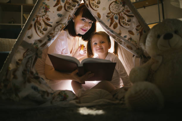 istock Mother reading fairytale to daughter during evening time 1367900272