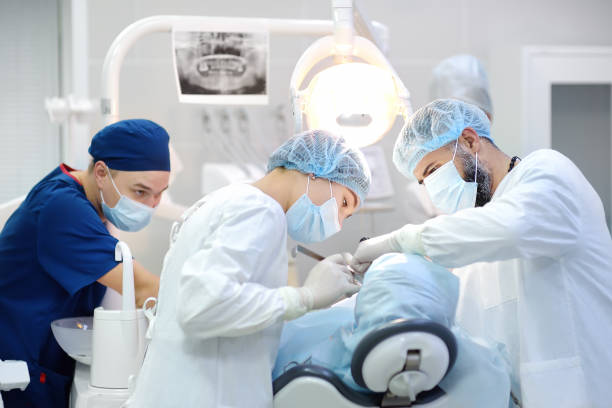 cirujano y enfermero durante una operación dental. paciente anestesiado en quirófano. instalación de implantes dentales en la clínica. - clinica dental fotografías e imágenes de stock