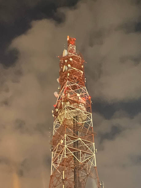istock Cell tower on night closeup view with white clouds on sky 1367902401