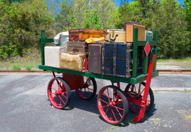 An antique railroad luggage cart loaded with vintage suitcases, trunks and valises at a Cape cod railroad station.