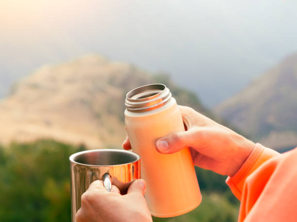 istock female hands with a mug and a thermos in nature 1367904012