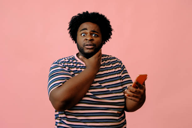 istock young african american man with a phone posing in the studio over pink background 1367904083