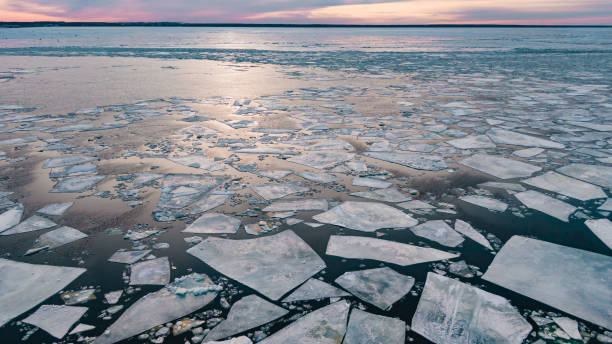 日没時に銀行の近くの穏やかな水面に壊れた氷の破片 - ice float ストックフォトと画像