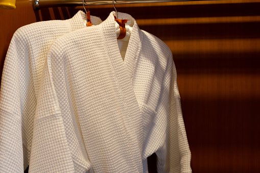 White bathrobe with wooden hangers in wardrobe