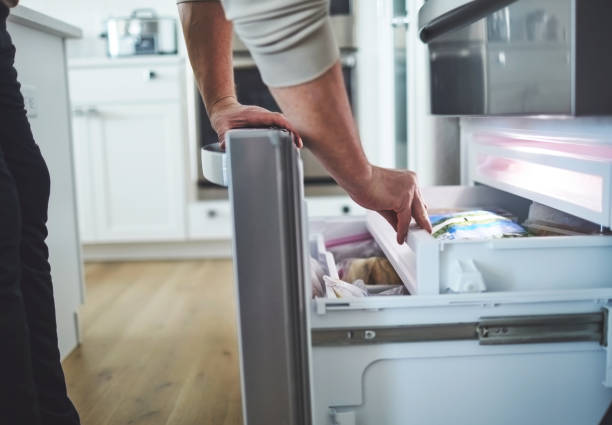 Unidentifiable male looking in an opened freezer drawer of a refrigerator Unidentifiable male looking in an opened freezer drawer of a refrigerator freezer stock pictures, royalty-free photos & images