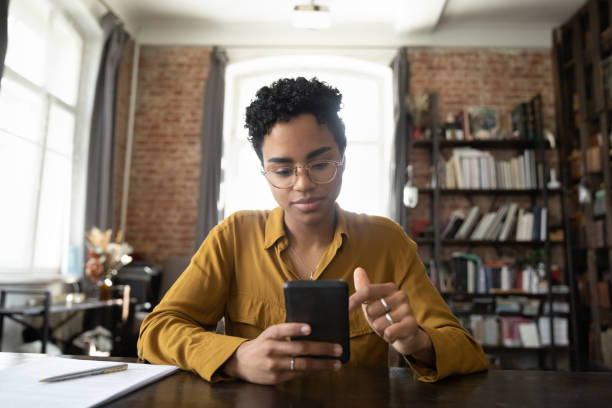 istock Concentrated young African American woman using cellphone in office. 1367907006