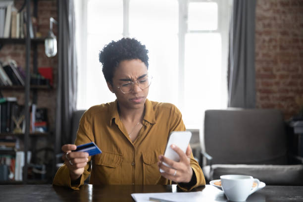 unglückliche junge afroamerikanerin, die probleme mit dem einkaufen im internet hat. - mobile phone telephone frustration women stock-fotos und bilder