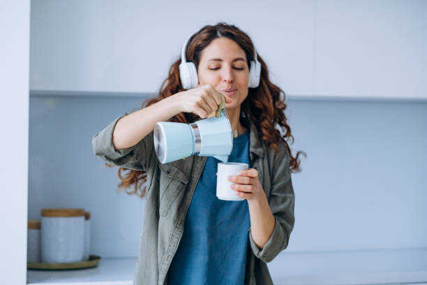 женщина танцует под музыку в наушниках с кофе в чашке - coffee pot audio стоковые фото и изображения