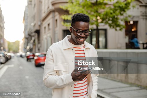 istock Young African-American man uses a mobile phone on the go 1367909982