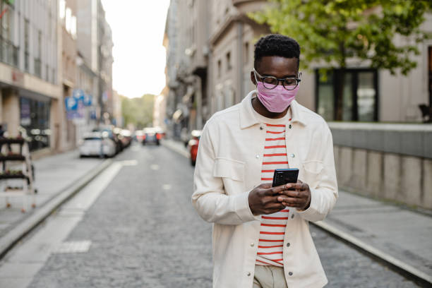 istock African-American young man walking and wearing protective face mask 1367910037