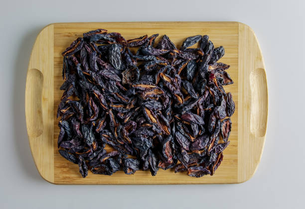 Background of dried black plums slices on a wooden board. Chips from dried fruits. Healthy food. Top view stock photo