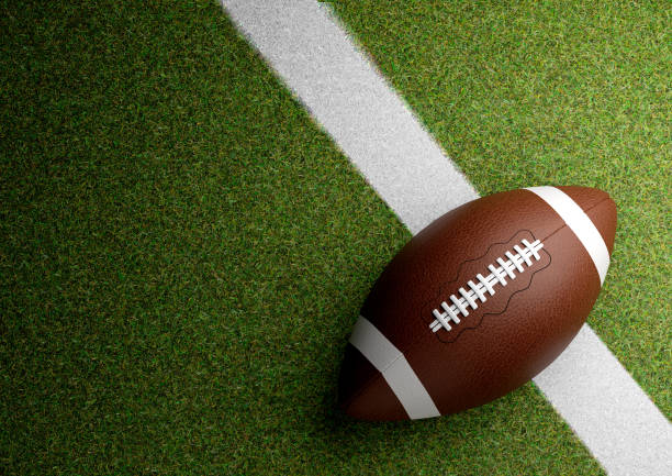 American football ball on stadium grass at night. Copy space stock photo