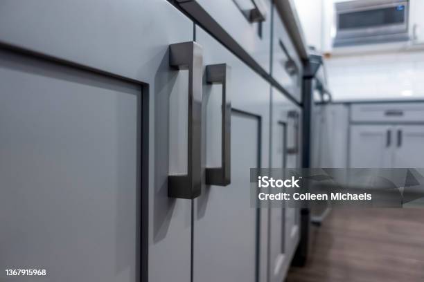 Low Angle View Of Gray Kitchen Cabinet Door Handles Inside A Large Beautiful Kitchen With Finished Hardwood Floors Stock Photo - Download Image Now