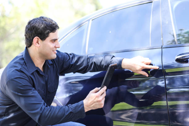 latin descent man inspects car for damages. insurance claims. - car insurance insurance agent damaged imagens e fotografias de stock