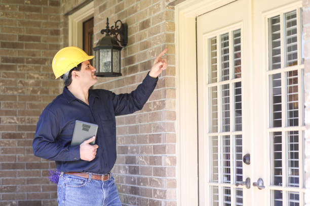 Latin descent man inspects home exterior. Contractor, inspector. stock photo