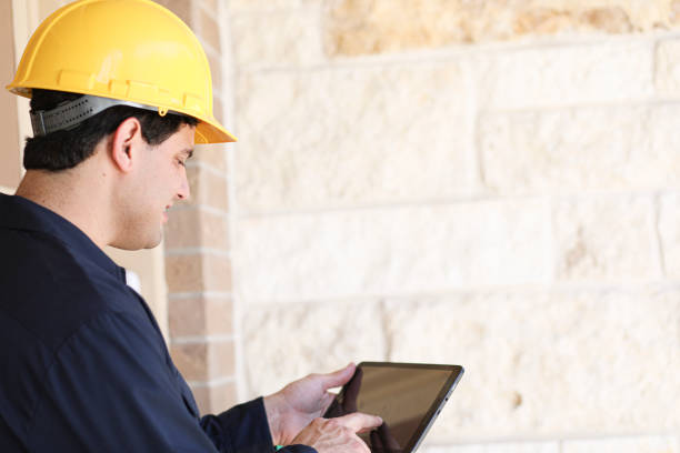 istock Latin descent man inspects home exterior. Contractor, inspector. 1367917122