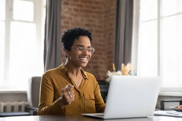 Photo of Overjoyed millennial African American woman getting win notification.