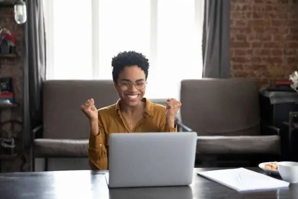 Photo of Happy laughing young African American woman celebrating internet success.