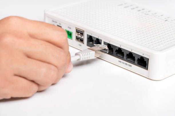 ルーターでネットワークケーブルを手で接続します。インターネットへのアクセス - network connection plug network server computer cable wireless technology ストックフォトと画像