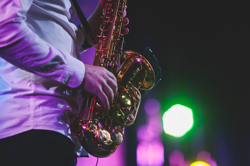 Concert view of a saxophonist, saxophone player with vocalist and musical during jazz orchestra performing music on stage\