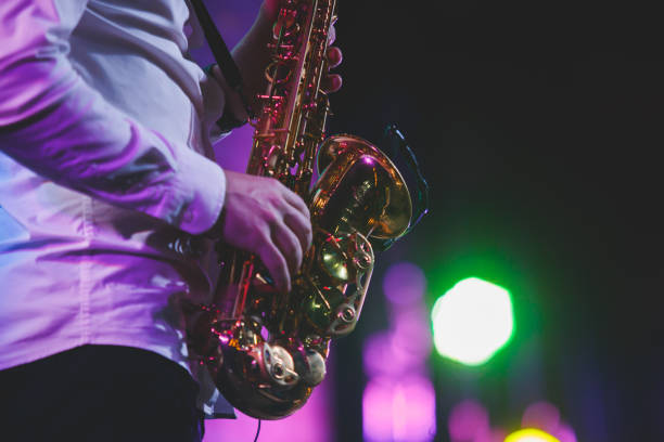 Concert view of a saxophonist, saxophone player with vocalist and musical during jazz orchestra performing music on stage stock photo