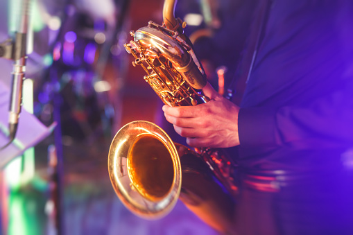 Concert view of a saxophone player with vocalist and musical jazz band in the background\