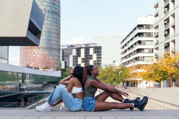 istock two young friends smile while sitting in the city 1367926773