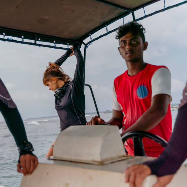 young captain, sri lankan man, control the boat with a group of divers on a way to the ocean. - men latin american and hispanic ethnicity southern european descent mature adult imagens e fotografias de stock