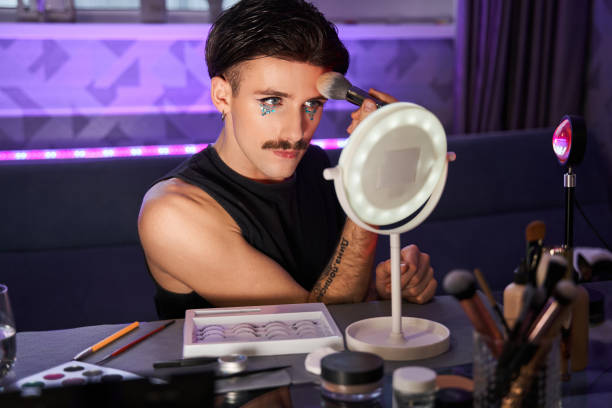 istock Man applying blushes with special brush and feeling attentive while doing make-up at home 1367930072