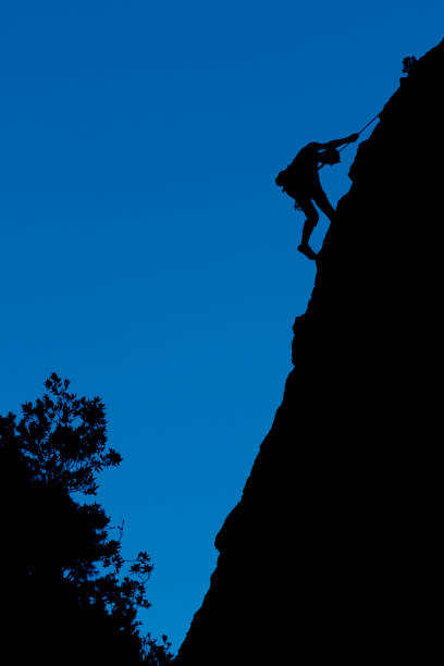 silhouette of a climber on a cliff and blue sky