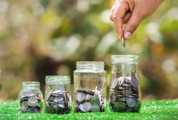istock hand holding coins putting into jug glass with money stack on green grass. concept saving finance and accounting concept 1367939237