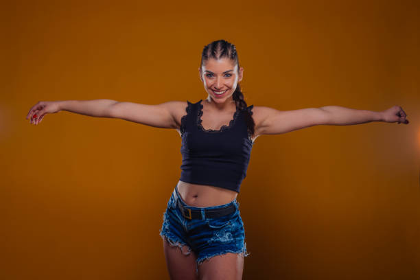 istock Attractive and cheerful female wearing casual summer clothes while posing with her hands up in the air inside a studio 1367939821