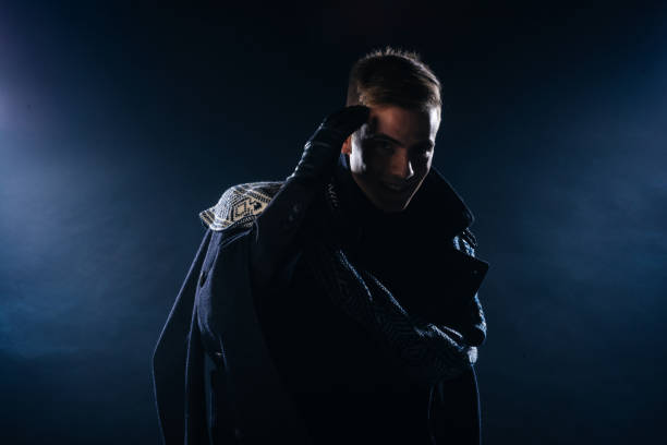 istock Portrait of a handsome with sharp jawline young man wearing a scarf while posing inside a studio on a black background. 1367940201