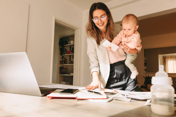istock Mom holding her baby while working in her home office 1367940939