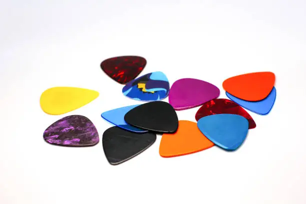 Close-up photo of multi-colored guitar picks against a white background.