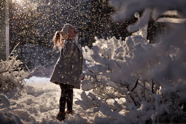 girl stands in snowdrift near bushes catching snowflakes in the dark