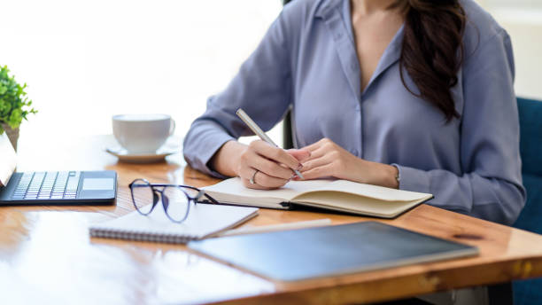 istock Close up. Businesswoman hand using pen taking notes in office. 1367946239