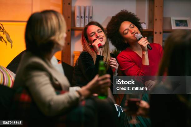 Happy Multicultural Friends Sitting At Home Laughing Singing And Having Fun On Karaoke Night Stock Photo - Download Image Now