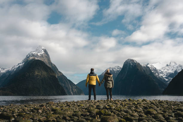 Couple holdings hands at the majestic landscape of fjords in Milford Sound, New Zealand stock photo