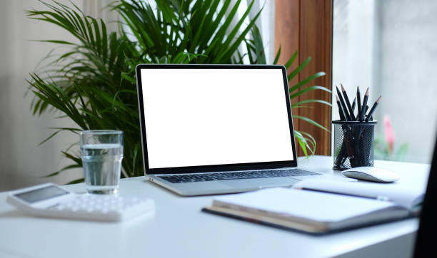 istock Mockup laptop computer, book, calculator, glass and pencil holder on white table. 1367949738