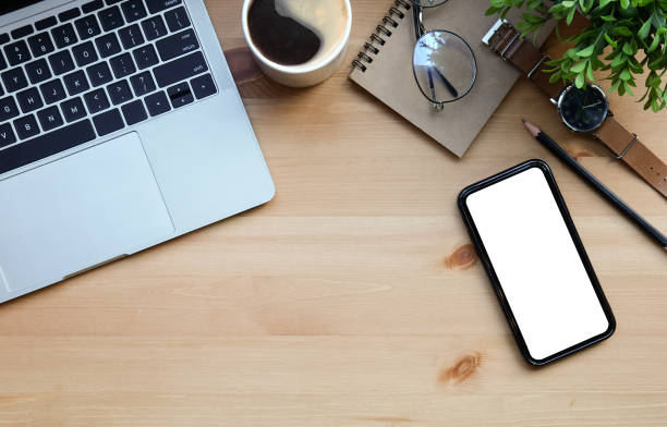 istock Top view mobile phone, computer laptop, notebook, coffee cup and plant on wooden table. 1367949795