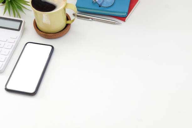 istock Smart phone, coffee cup, calculator and notebooks on white table. 1367950004