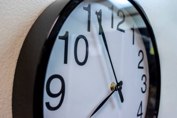 istock Close up focus on a large, black and white wall clock hung up on a beige colored wall 1367951966