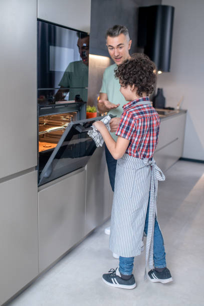 istock Boy opening oven and happy dad near 1367953288