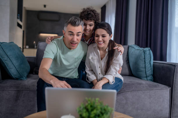 istock Boy hugging parents looking at laptop sitting on sofa 1367953329