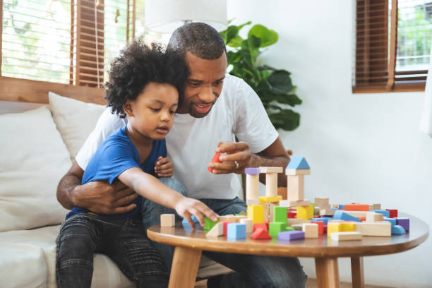 pai afro-americano e seu filho pequeno jogando torre de construção com brinquedo bloco de madeira - block child play toy - fotografias e filmes do acervo